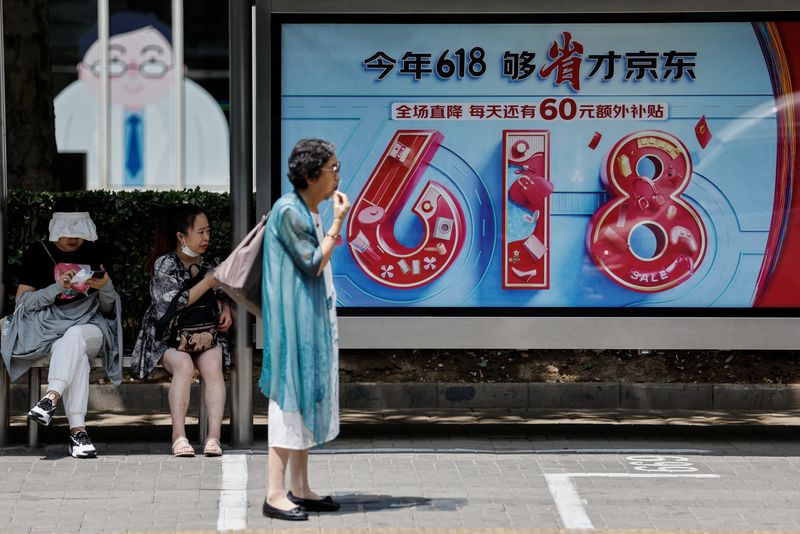 &copy; Reuters. People wait for bus near a billboard of JD.com advertisement for the "618" shopping festival, in Beijing, China June 12, 2023. REUTERS/Tingshu Wang