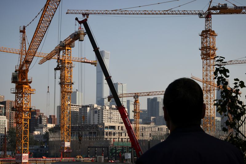 &copy; Reuters. A person looks towards cranes in front of the skyline of the Central Business District (CBD) in Beijing, China, October 18, 2021. REUTERS/Thomas Peter/File Photo