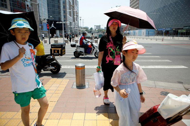 &copy; Reuters. أشخاص يضعون قبعات واقية من حرارة الشمس في بكين يوم الجمعة. تصوير: فلورنس لو.