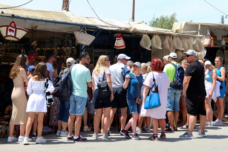 &copy; Reuters. سياح يقفون بجانب محل لبيع الهدايا التذكارية في سيدي بوسعيد في تونس يوم 13 يونيو حزيران 2023. تصوير: جهاد عبد اللاوي - رويترز.   
