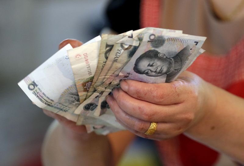 &copy; Reuters. Un vendeur tient des billets de yuan chinois sur un marché de Pékin. /Photo prise le 12 août 2015/REUTERS/Jason Lee