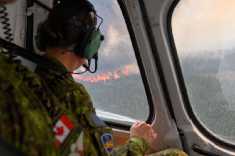 &copy; Reuters. جندي من اللواء الميكانيكي الكندي الخامس يشاهد حريقا هائلا من قمرة طائرة مروحية تابعة للقوات الكندية تقوم بمسح المنطقة بالقرب من ميستيسيني 