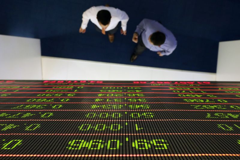 &copy; Reuters. متداولون يسيرون تحت شاشة تعرض حركة الأسهم في سوق دبي المالية. الصورة من أرشيف رويترز 