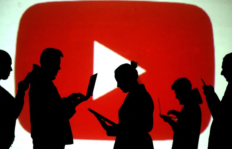 &copy; Reuters. FILE PHOTO: Silhouettes of laptop and mobile device users are seen next to a screen projection of the YouTube logo in this picture illustration taken March 28, 2018. REUTERS/Dado Ruvic//File Photo