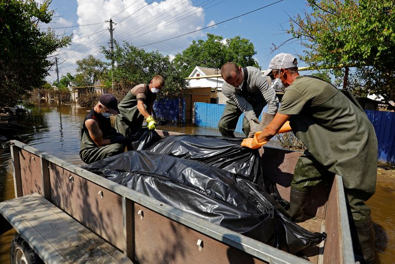 © Reuters. متطوعون وعمال بمجلس البلدية يضعون حقيبتين بهما جثتان تم انتشالهما من المنازل المغمورة بمياه الفيضانات في 16 يونيو حزيران 2023  جراء انهيار سد كاخوفكا في خيرسون بأوكرانيا . 