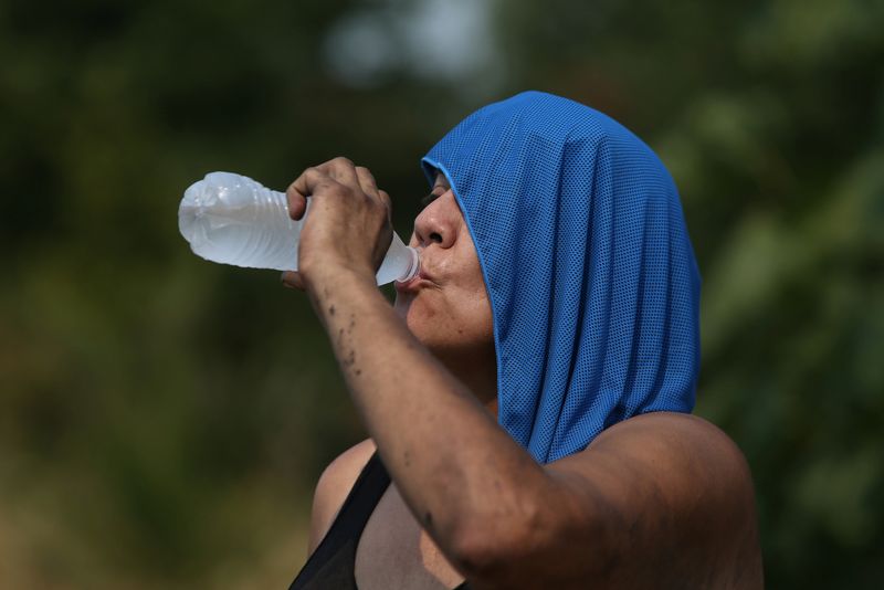 &copy; Reuters. FILE PHOTO: Cris, who preferred not to give her last name, drinks water near her campsite during a heatwave in Salem, Oregon, U.S. August 12, 2021. REUTERS/Alisha Jucevic/File Photo
