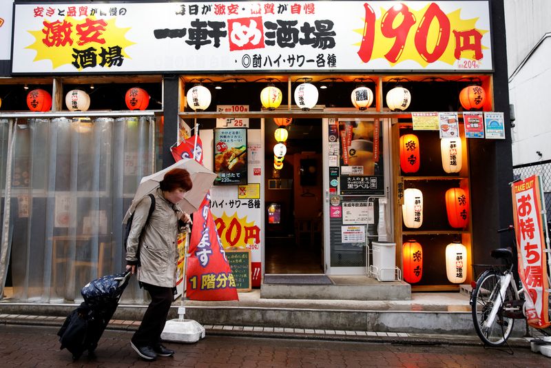 © Reuters. A woman walks in front of a cheap izakaya (Japanese tavern) in Tokyo, Japan, March 24, 2023. REUTERS/Androniki Christodoulou/FILE PHOTO