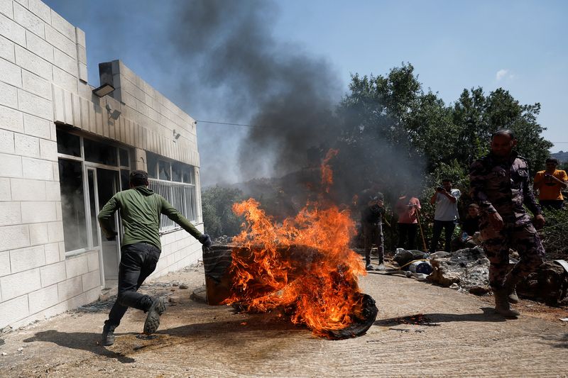 &copy; Reuters. Homen palestino foge de objeto com fogo após ataque de colonos israelenses, em Ramallah, na Cisjordânia ocupada
21/06/2023
REUTERS/Mohamad Torokman