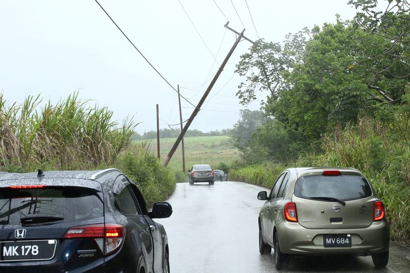 © Reuters. Cars pass a leaning power pole after Tropical Storm Bret passed north of the island, in St. Thomas, Barbados June 22, 2023.  REUTERS/Nigel R. Browne