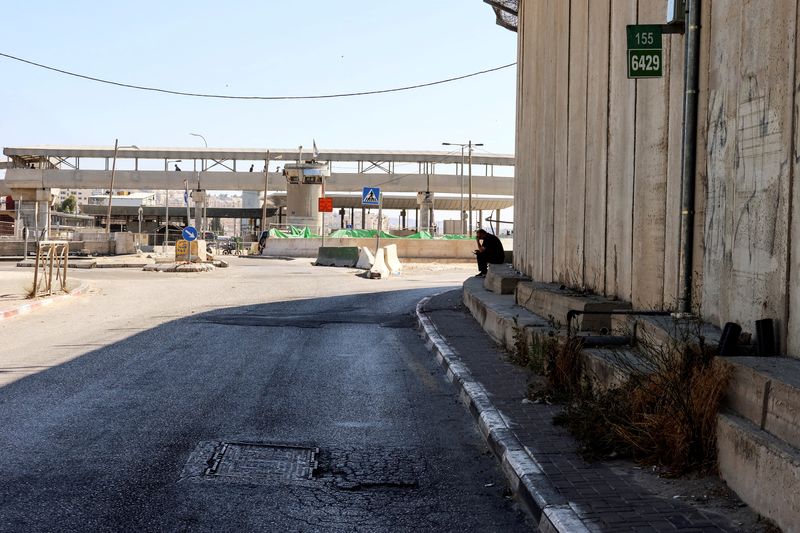 &copy; Reuters. رجل يجلس بالقرب من حاجز قلنديا بعدما قالت الشرطة الإسرائيلية إن من يشتبه في أنه مسلح فلسطيني فتح النار على نقطة تفتيش إسرائيلية بالضفة الغر