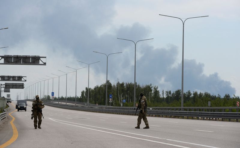 &copy; Reuters. Fighters of Wagner private mercenary group walk during a stop on M-4 highway, which links the capital Moscow with Russia's southern cities, with smoke from a burning fuel tank at an oil depot seen in the background, near Voronezh, Russia, June 24, 2023. R