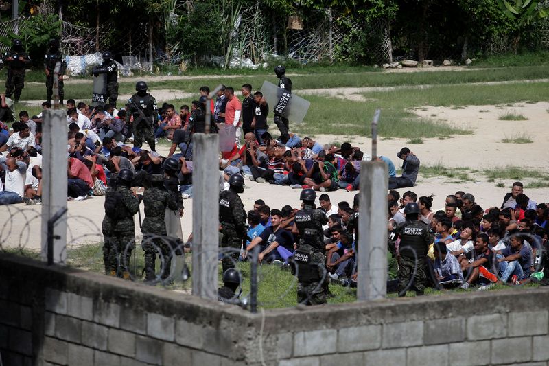 © Reuters. Members of the Military Police of Public Order stand guard as inmates sit in the yard at Tamara prison after the Honduras Armed Forces took over the control of the prisons nationwide as part of the 