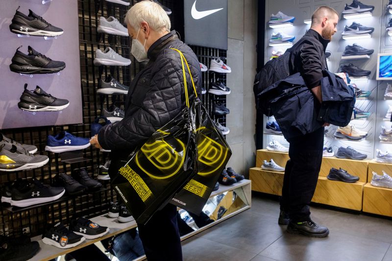 &copy; Reuters. FILE PHOTO: A shopper carrying JD Sports bags looks at footwear at a JD Sports store in London, Britain, November 17, 2021. REUTERS/May James