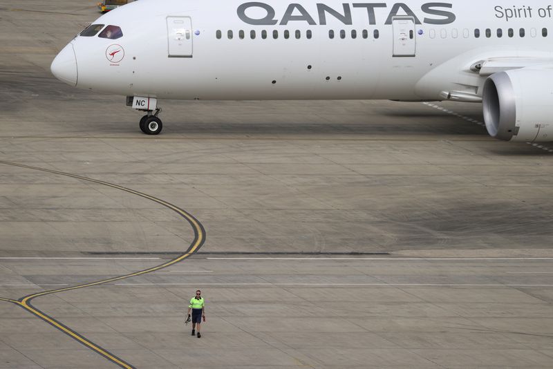 © Reuters. FILE PHOTO: A ground worker walking near a Qantas plane is seen from the international terminal at Sydney Airport, as countries react to the new coronavirus Omicron variant amid the coronavirus disease (COVID-19) pandemic, in Sydney, Australia, November 29, 2021.  REUTERS/Loren Elliott/File Photo