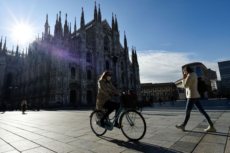 &copy; Reuters. FILE PHOTO: People passes by the Duomo Cathedral, after Lombardy was downgraded from a red to an orange zone, loosening the coronavirus disease (COVID-19) restrictions including allowing non-essential shops to re-open, in Milan, Italy, April 13, 2021. REU