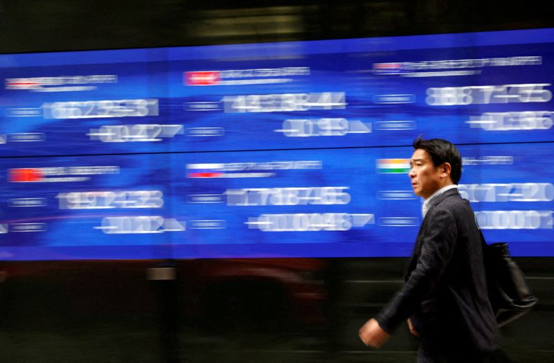 &copy; Reuters. رجل يمر أمام لوحة إلكترونية تعرض حركة تداول الأسهم على مؤشر نيكي الياباني خارج بنك بالعاصمة طوكيو في 
22 مارس آذار 2023 . تصوير : إيسي كاتو - رويت