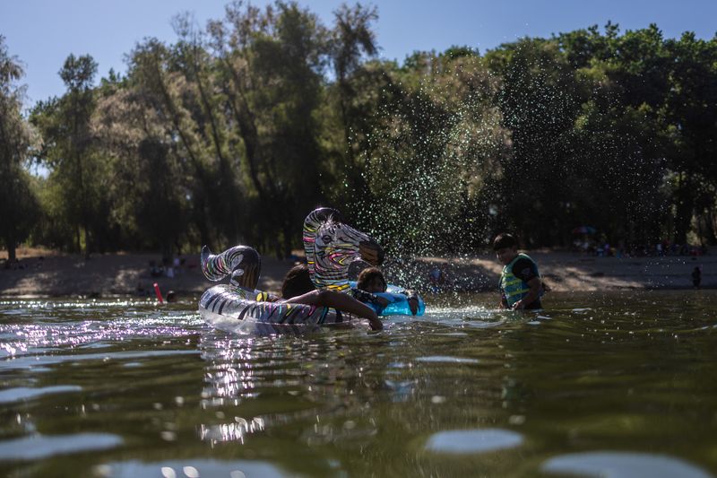 © Reuters. Children refresh themselves at the Feather River, as the temperature rises over 100 degrees Fahrenheit (38 Celsius), in Yuba City, California, U.S., June 30, 2023. REUTERS/Carlos Barria