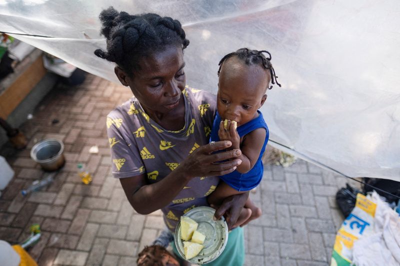 © Reuters. FILE PHOTO: A woman feeds her baby at the Hugo Chavez Square where they shelter from gang war violence in Port-au-Prince, Haiti October 16, 2022. REUTERS/Ricardo Arduengo/File Photo