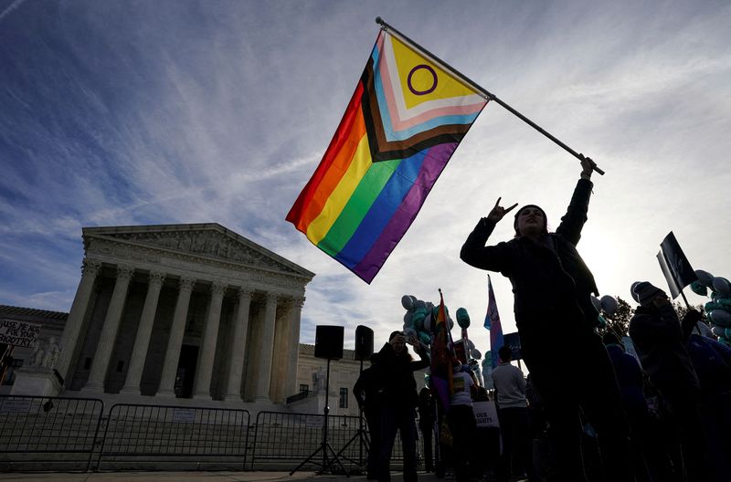 © Reuters. FILE PHOTO: A protester waves an LGBT rights 'pride flag' as activists gather outside the U.S. Supreme Court, December 5, 2022. REUTERS/Kevin Lamarque