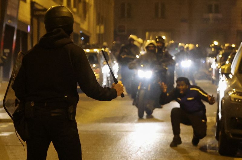 © Reuters. A person reacts while a police officer holds a baton during protests following the death of Nahel, a 17-year-old teenager killed by a French police officer in Nanterre during a traffic stop, in Paris, France, July 2, 2023. REUTERS/Nacho Doce