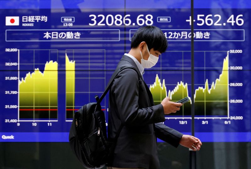 &copy; Reuters. رجل يسير أمام لوحة إلكترونية تعرض حركة تداول الأسهم على مؤشر نيكي الياباني خارج بنك بطوكيو في الخامس من يونيو حزيران 2023 . تصوير : إيسي كاتو - ر
