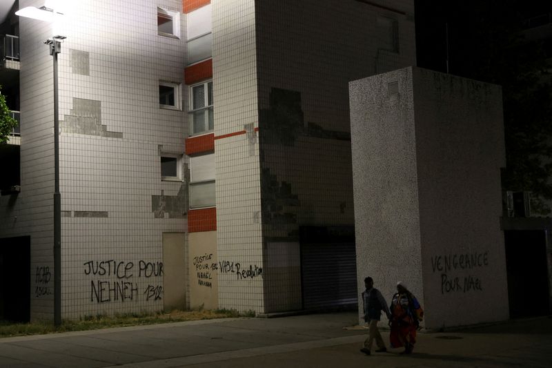 &copy; Reuters. Des habitants passent devant des phrases écrites sur les murs des immeubles de Nanterre, le quartier du jeune de 17 ans tué par un policier lors d'un contrôle routier. /Photo prise le 2 juillet 2023/REUTERS/Nacho Doce.