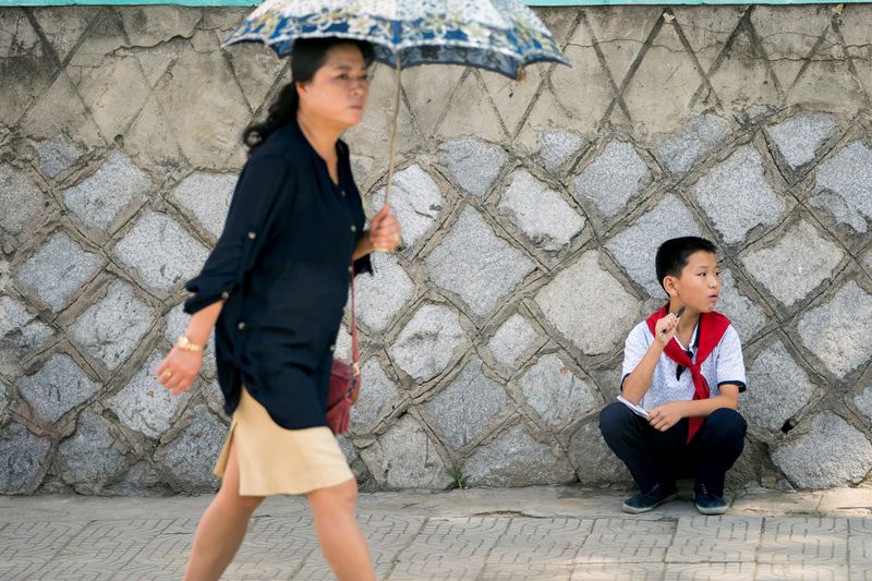 &copy; Reuters. امرأة تمر بصبي جالس في أحد شوارع بيونج يانج في كوريا الشمالية. صورة من أرشيف رويترز.