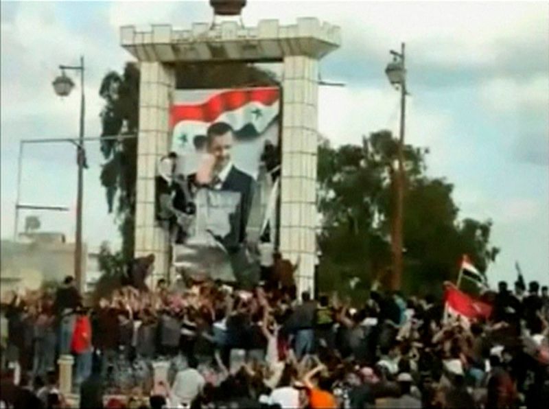 &copy; Reuters. صورة ثابتة مأخوذة من مقطع فيديو لمتظاهرين يشوهون ملصق عملاق للرئيس السوري بشار الأسد في درعا بسوريا يوم 25 مارس آذار 2011. بصورة من أرشيف رويتر