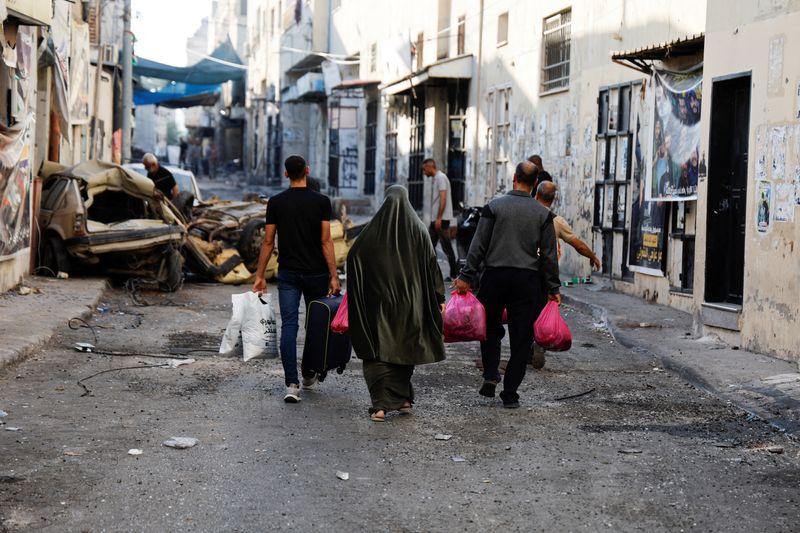 © Reuters. People carry their belongings on the street after the Israeli army's withdrawal from the Jenin camp, in Jenin, in the Israeli-occupied West Bank July 5, 2023. REUTERS/Ammar Awad