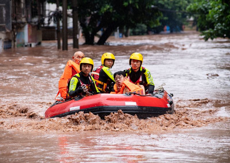 © Reuters. Des secouristes évacuent des habitants d'une rue inondée après de fortes pluies à Chongqing, en Chine. /Photo prise le 4 juillet 2023/REUTERS/cnsphoto 