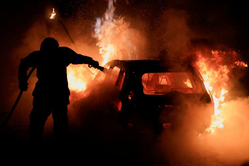 © Reuters. Un pompier français tente d'éteindre une voiture en feu après des émeutes à Tourcoing, en France. /Photo prise le 2 juillet 2023/REUTERS/Pascal Rossignol