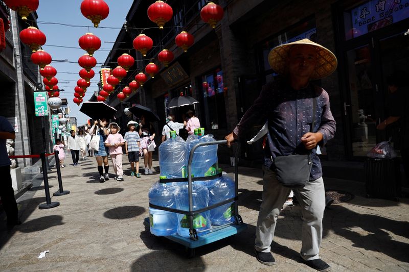 &copy; Reuters. A man pulls a cart carrying jugs of water amid the orange alert for heatwave, at a hutong alley in Beijing, China July 5, 2023. REUTERS/Tingshu Wang