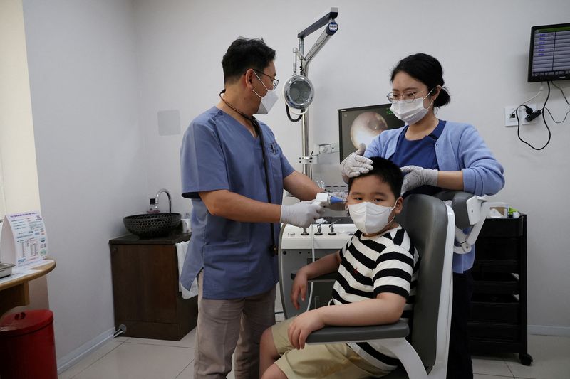 &copy; Reuters. طبيب أطفال يفحص طفلا في عيادته في سول سوم 14 يونيو حزيران 2023.  تصوير: كيم هونج جي - رويترز. 