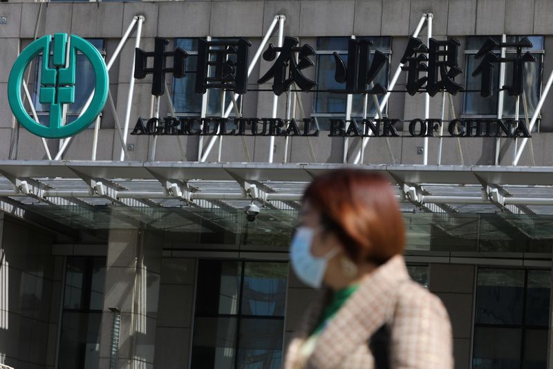 &copy; Reuters. FILE PHOTO: A woman walks past an office building of Agricultural Bank of China, in Beijing, China March 29, 2021. REUTERS/Tingshu Wang