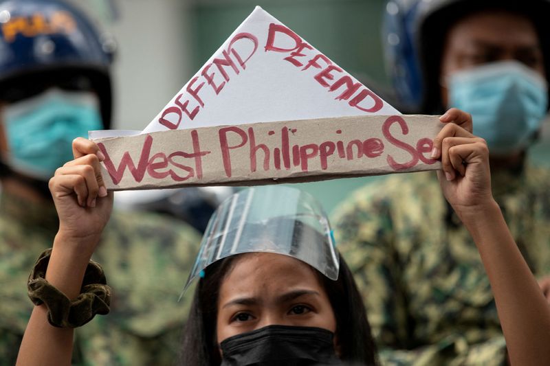 &copy; Reuters. ناشط يحمل لافتة مكتوب عليها "دافع عن بحر الفلبين الغربي" أثناء احتجاج خارج القنصلية الصينية في الحي المالي في مانيلا في صورة من أرشيف رويترز.