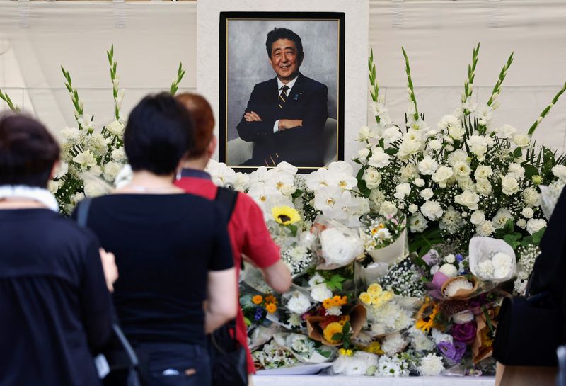 &copy; Reuters. مشاركون في تأبين رئيس الوزراء الياباني شينزو آبي يضعون الزهور ويصلون من أجله في طوكيو يوم السبت خلال إحياء ذكرى عام من اغتياله. تصوير: إيسي ك