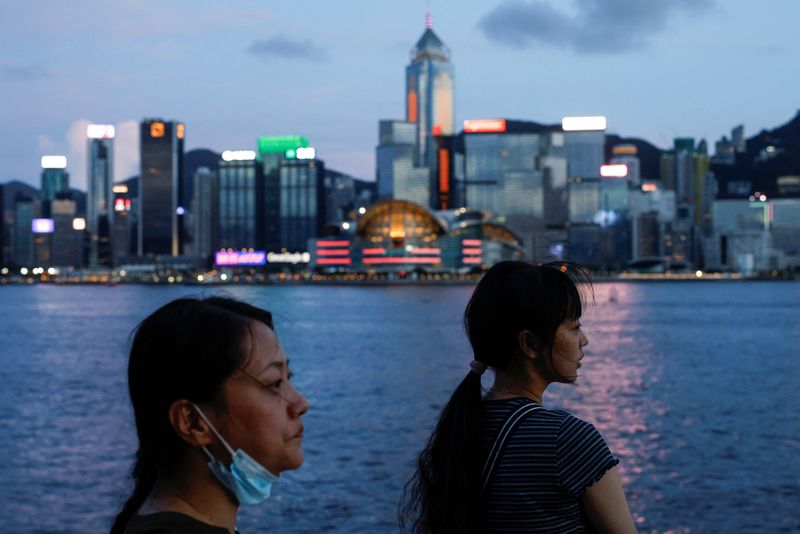 &copy; Reuters. FILE PHOTO: Tourists relax on the waterfront in front of Victoria Harbour, with the iconic skyline buildings as a backdrop, in Hong Kong, China June 28, 2023. REUTERS/Tyrone Siu