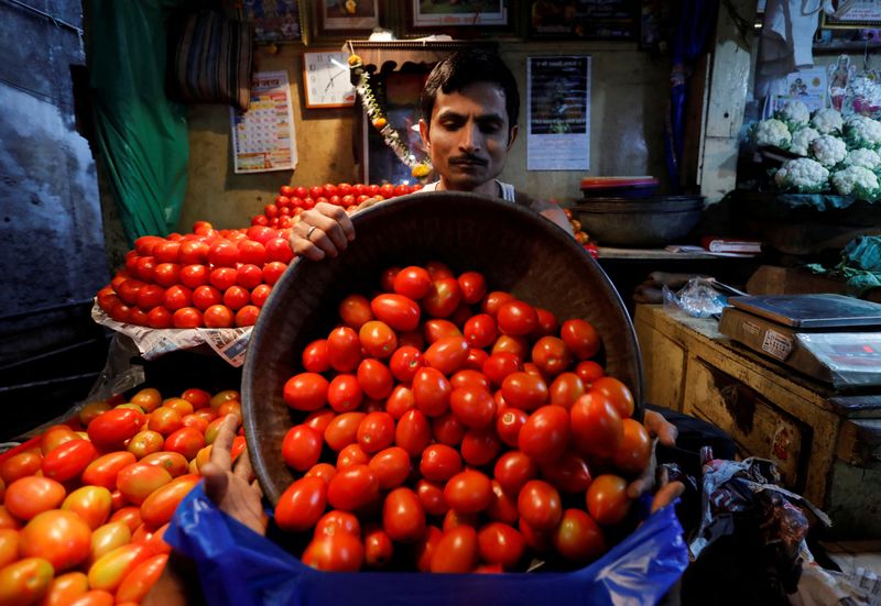 &copy; Reuters. FILE PHOTO: A vendor loads tomatoes in a bag for a customer at a wholesale vegetable market in Mumbai, India, March 14, 2018. REUTERS/Danish Siddiqui/File Photo