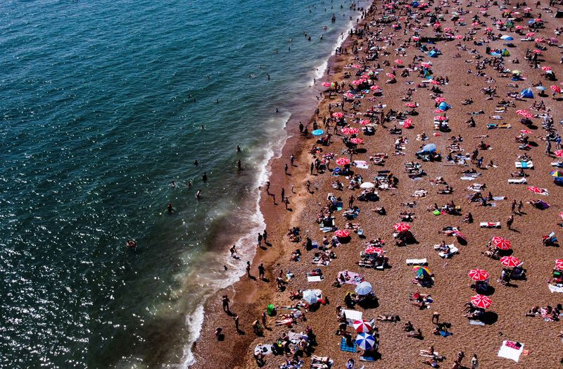 © Reuters. FILE PHOTO: People enjoy the sun on the beach in Brighton, Britain, June 25, 2023. REUTERS/Carlos Jasso/File Photo