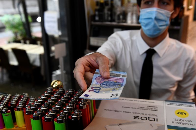 &copy; Reuters. Un uomo usa i contanti per pagare gli articoli durante lo shopping a Milano, Italia, 2 ottobre 2020.   REUTERS/Flavio Lo Scalzo