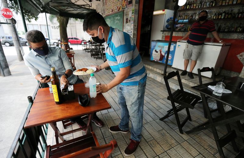 &copy; Reuters. FILE PHOTO: A waiter serves a customer at a bar after the reopening of gyms, restaurants and sport facilities on the beaches as the city eases restrictions, amid the coronavirus disease (COVID-19) outbreak in Rio de Janeiro, Brazil July 2, 2020. REUTERS/S