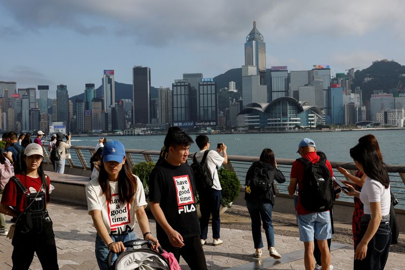 &copy; Reuters. FILE PHOTO: Mainland Chinese tourists walk in front of the skyline of buildings at Tsim Sha Tsui, in Hong Kong, China May 2, 2023. REUTERS/Tyrone Siu