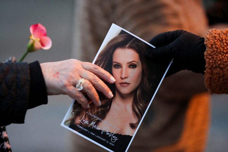 &copy; Reuters. FILE PHOTO: A music fan hands a picture of Lisa Marie Presley to another fan as they attend a public memorial for her, the only daughter of the "King of Rock 'n' Roll," Elvis Presley, at Graceland Mansion in Memphis, Tennessee, U.S. January 22, 2023.  REU