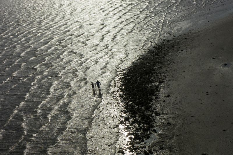 © Reuters. A father and child walk the shoreline searching for shells during hot weather in Texas City, Texas, U.S., July 15, 2023.  REUTERS/Adrees Latif
