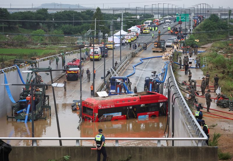 © Reuters. Rescue workers are seen near a recovered electric bus during a search and rescue operation near an underpass that has been submerged by a flooded river caused by torrential rain in Cheongju, South Korea, July 16, 2023.   REUTERS/Kim Hong-ji