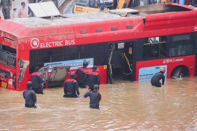 &copy; Reuters. عمال الإنقاذ يشاركون في عمليات البحث و الإنقاذ قرب حافلة غمرتها مياه الفيضانات الناجمة عن الأمطار الغزيرة في كوريا الجنوبية يوم الأحد . تصو