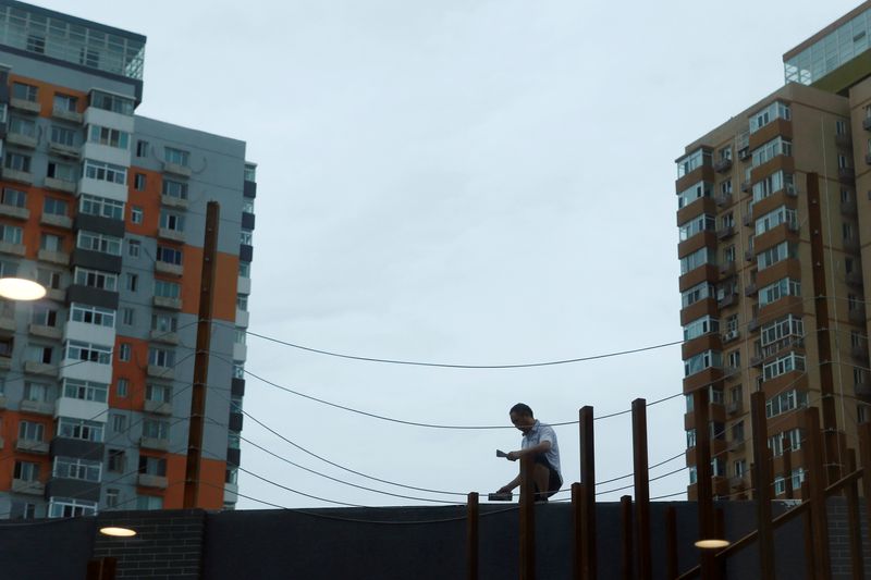 &copy; Reuters. FILE PHOTO-Lights are seen reflected on a window as a man works on renovating an office building near residential buildings in Beijing, China August 12, 2019. Picture taken August 12, 2019 through a window.  REUTERS/Florence Lo/file photo