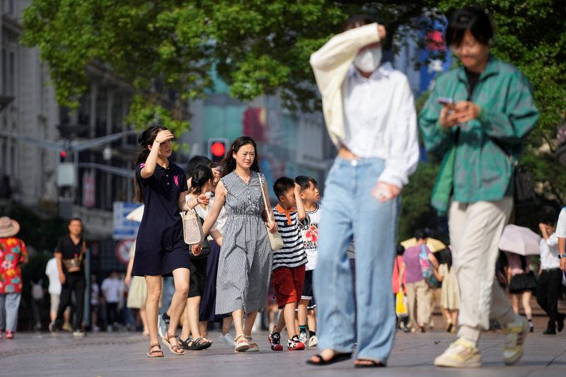 &copy; Reuters. Les gens marchent dans la rue en se protégeant du soleil, au milieu d'une alerte canicule à Shanghai. /Photo prise le 11 juillet 2023/REUTERS/Aly Song