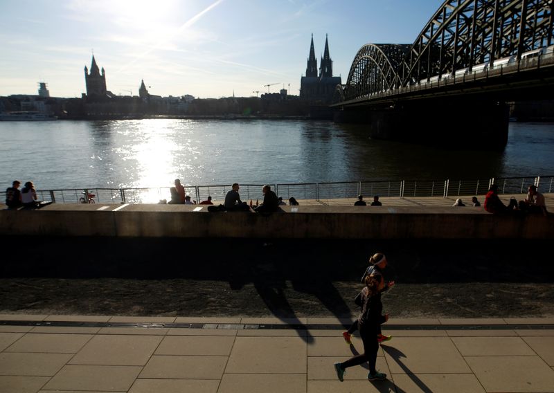 © Reuters. People sit and run near the river Rhine in Cologne, Germany, March 17, 2020. REUTERS/Thilo Schmuelgen/Files