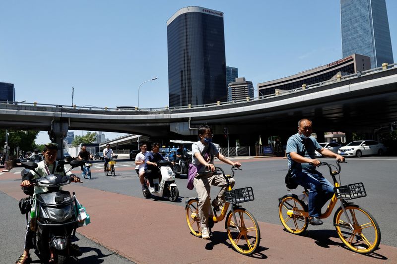 © Reuters. FILE PHOTO: People ride bikes and scooters on a street at Beijing's Central Business District, in Beijing, China June 21, 2023. REUTERS/Tingshu Wang